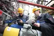 Ingenieure mit Schutzhelmen inspizieren Industrieanlagen und mechanische Dichtungen während Wartungsarbeiten in einer Verarbeitungsanlage.